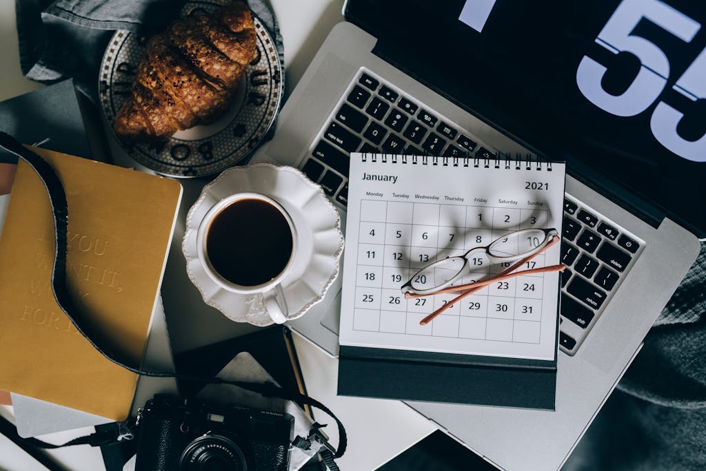 Calendar on a Laptop Beside a Cup of Black Coffee